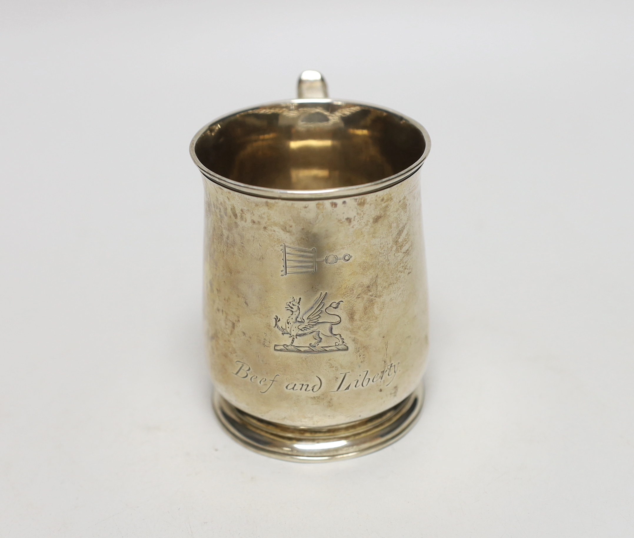 A George II silver half pint mug, engraved with a crest and the motto 'Beef and Liberty', makers mark rubbed, London 1730, 9.5cm, 194 grams